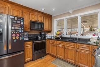 kitchen with dark countertops, brown cabinets, stainless steel appliances, and a sink