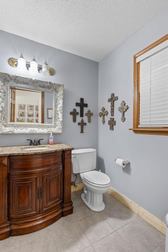 half bath with vanity, baseboards, a textured ceiling, tile patterned floors, and toilet