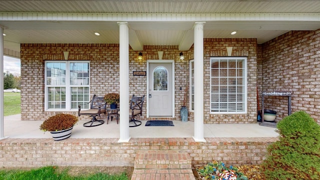 entrance to property featuring brick siding and covered porch