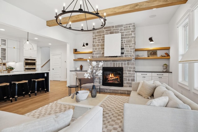 living area featuring light wood finished floors, recessed lighting, a fireplace, stairs, and beamed ceiling