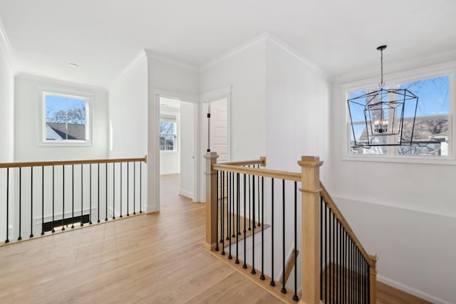 hallway featuring an upstairs landing, crown molding, baseboards, and wood finished floors