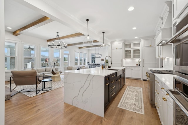 kitchen featuring light wood-style flooring, appliances with stainless steel finishes, white cabinets, and decorative backsplash