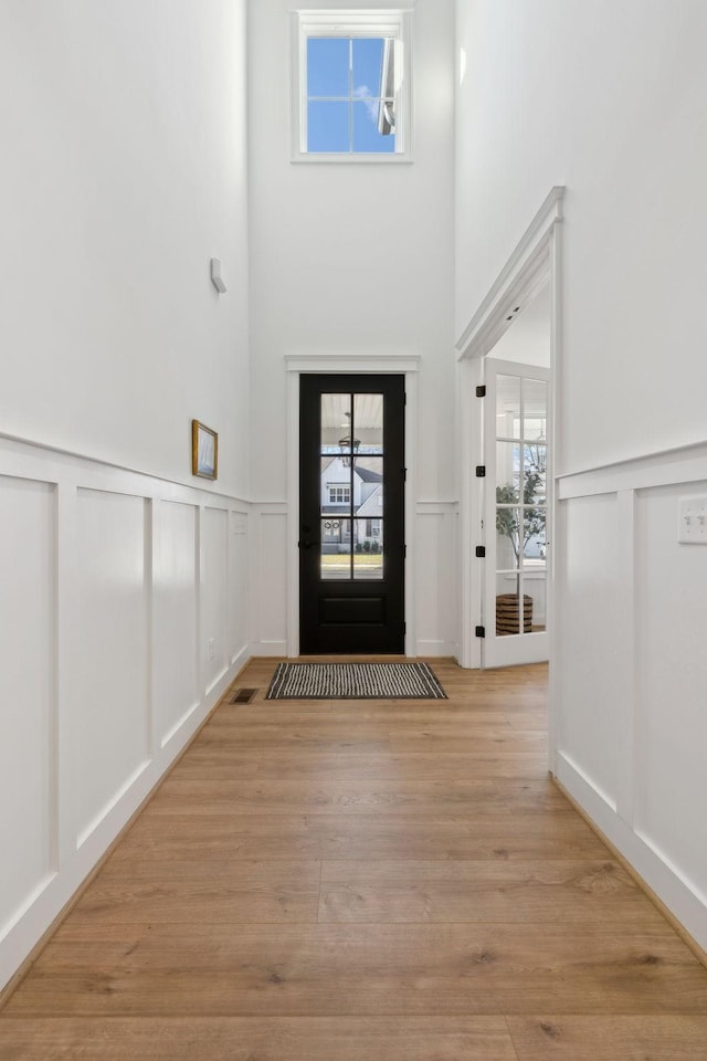 foyer featuring a decorative wall, light wood-style flooring, and visible vents