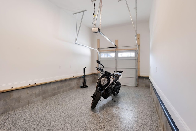 garage featuring concrete block wall and a garage door opener