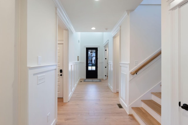 entryway with stairway, visible vents, a wainscoted wall, light wood finished floors, and a decorative wall