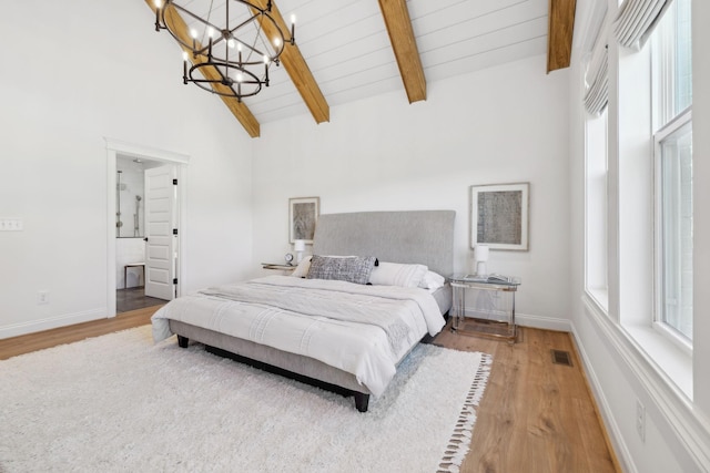 bedroom with wood finished floors, visible vents, baseboards, vaulted ceiling with beams, and a notable chandelier