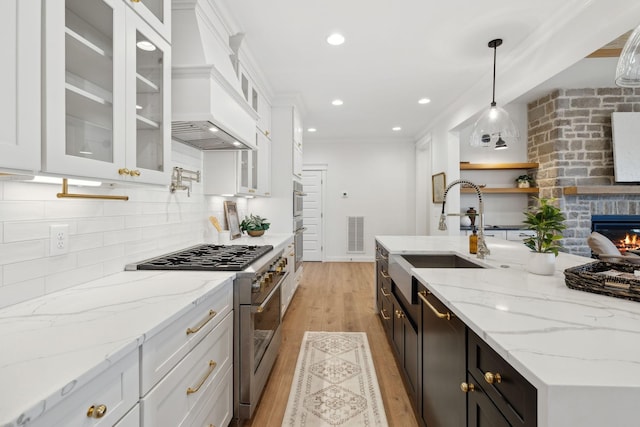 kitchen with visible vents, a sink, white cabinetry, appliances with stainless steel finishes, and custom exhaust hood