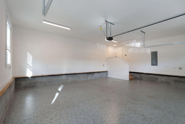 garage with concrete block wall, electric panel, and a garage door opener