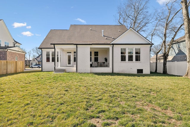 rear view of house featuring brick siding, a lawn, and fence