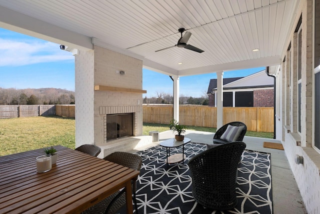 view of patio / terrace featuring an outdoor living space with a fireplace, a fenced backyard, and ceiling fan