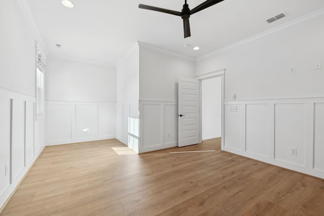 unfurnished bedroom with visible vents, light wood-style flooring, recessed lighting, crown molding, and a decorative wall