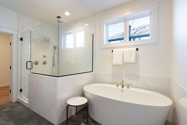 full bathroom featuring tile walls, a freestanding tub, recessed lighting, and a shower stall