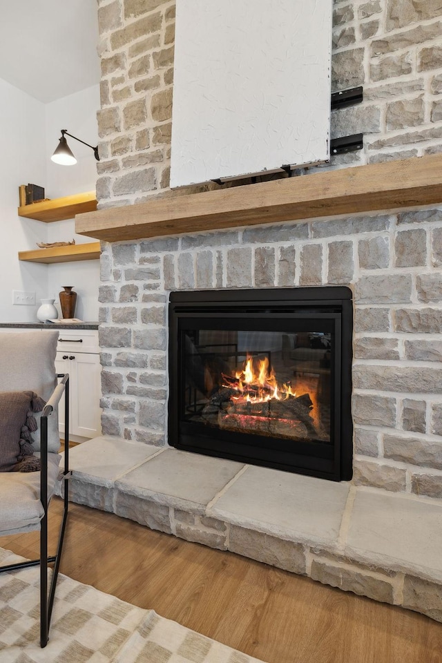 details with a stone fireplace and wood finished floors