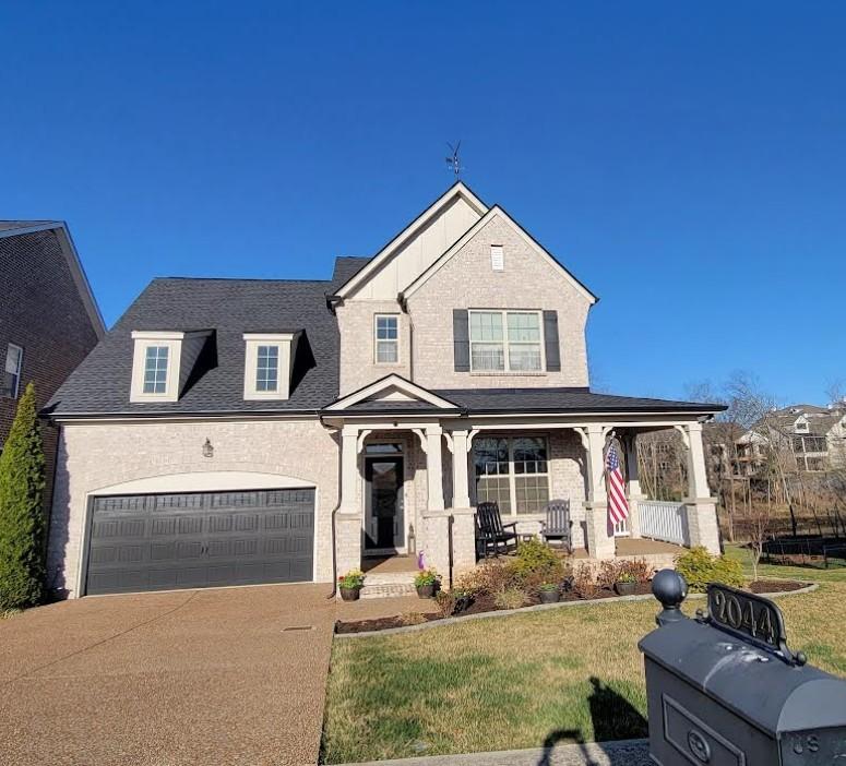 view of front facade featuring covered porch, driveway, a front yard, and a garage