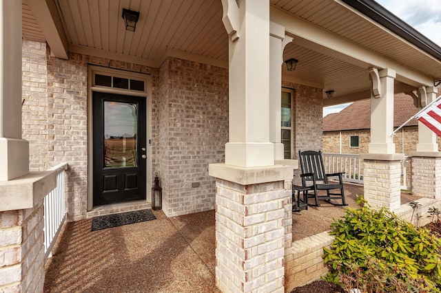 property entrance with a porch and brick siding