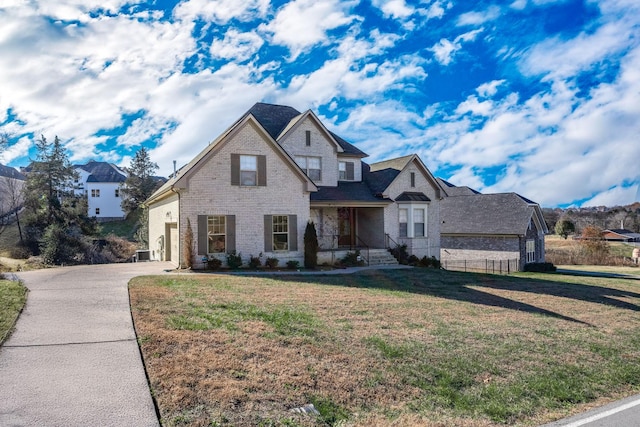 view of front of home featuring fence, driveway, a front lawn, a garage, and brick siding