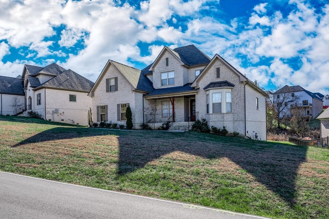 french country inspired facade featuring brick siding and a front yard