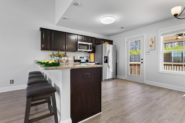 kitchen featuring a breakfast bar area, visible vents, baseboards, light wood-style flooring, and stainless steel appliances