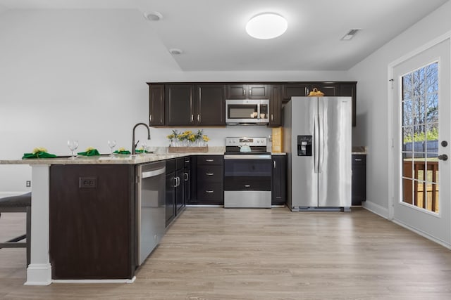 kitchen with visible vents, light wood-style flooring, appliances with stainless steel finishes, and a breakfast bar area