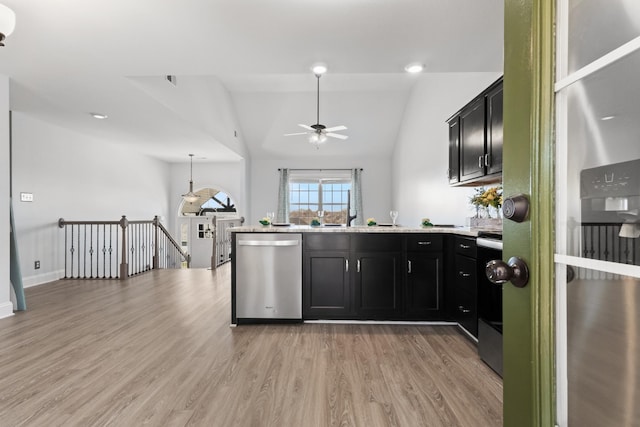 kitchen featuring light wood-type flooring, a peninsula, light countertops, appliances with stainless steel finishes, and dark cabinets