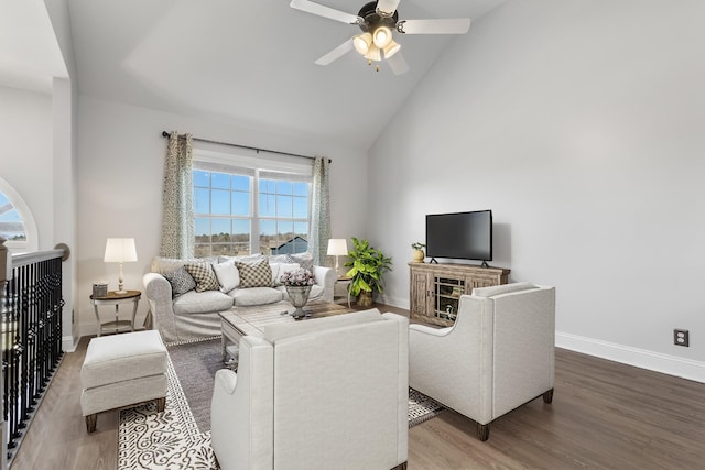 living room featuring baseboards, high vaulted ceiling, wood finished floors, and a ceiling fan