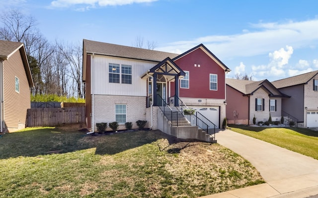 raised ranch with brick siding, concrete driveway, a front lawn, and fence