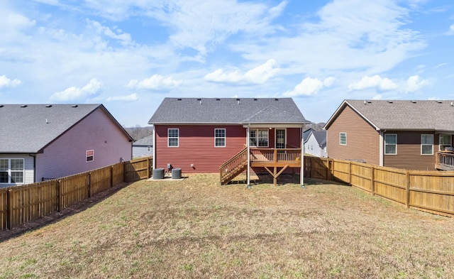 rear view of house featuring a wooden deck, central AC unit, a lawn, and a fenced backyard