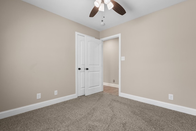 carpeted spare room with a ceiling fan and baseboards