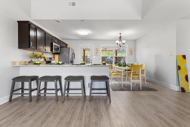 kitchen featuring visible vents, light wood-style flooring, a peninsula, appliances with stainless steel finishes, and light countertops