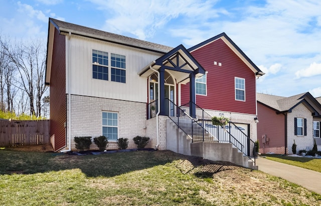 view of front facade with a front lawn, fence, brick siding, and driveway