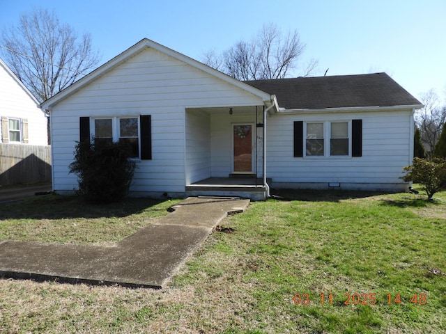 ranch-style home featuring roof with shingles, a front yard, and fence