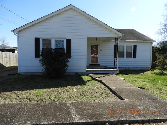 view of front facade featuring covered porch, roof with shingles, a front lawn, and fence