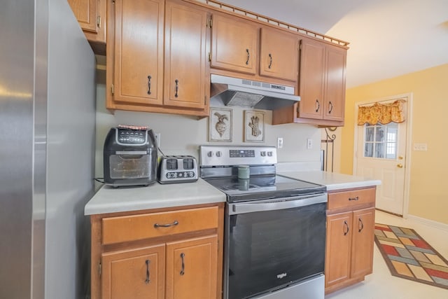 kitchen featuring light countertops, appliances with stainless steel finishes, baseboards, and under cabinet range hood