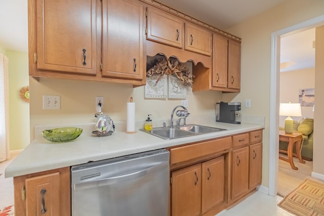 kitchen featuring stainless steel dishwasher, light countertops, baseboards, and a sink