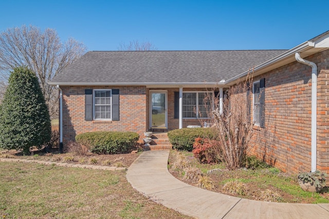 view of front of home featuring brick siding and roof with shingles