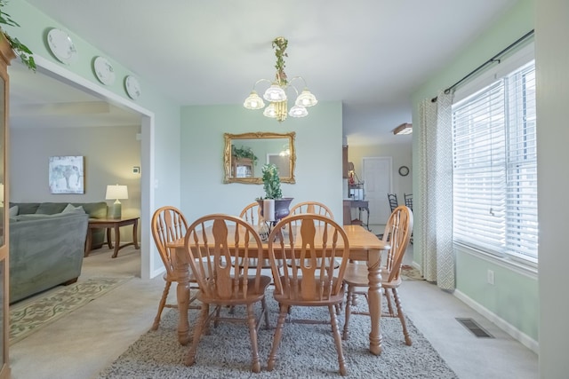 dining area featuring light carpet, visible vents, baseboards, and an inviting chandelier