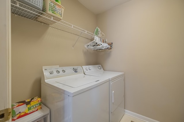 clothes washing area with laundry area, baseboards, and independent washer and dryer