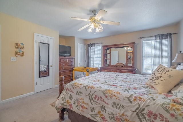 bedroom featuring ceiling fan, multiple windows, baseboards, and light carpet