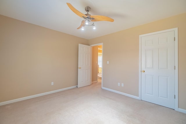 unfurnished bedroom with light carpet, a ceiling fan, and baseboards