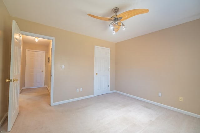 unfurnished bedroom with light colored carpet, a ceiling fan, and baseboards