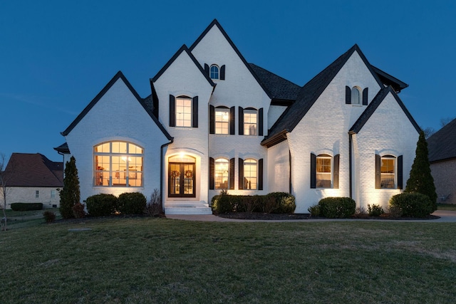 french provincial home featuring brick siding, french doors, and a front lawn