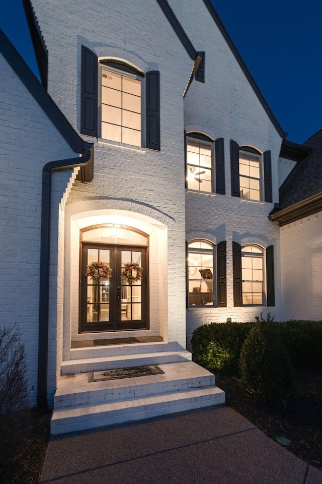 view of exterior entry featuring french doors and brick siding