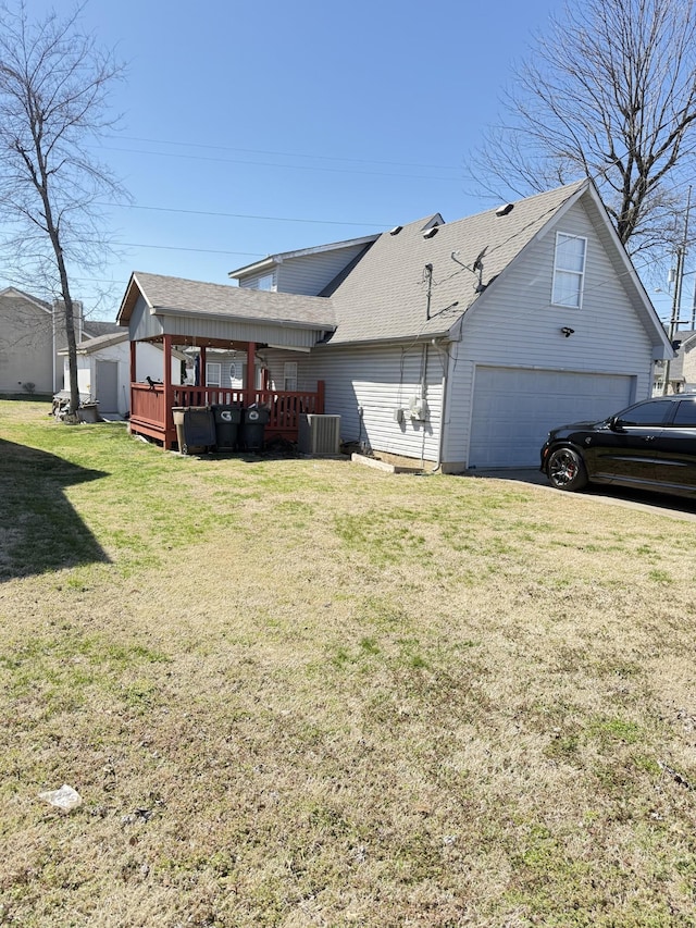 exterior space with cooling unit, a wooden deck, a shingled roof, a garage, and a lawn