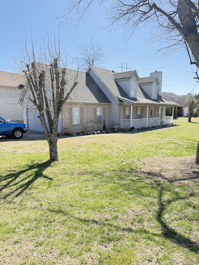 view of front of home with brick siding, a shingled roof, a front yard, covered porch, and an attached garage