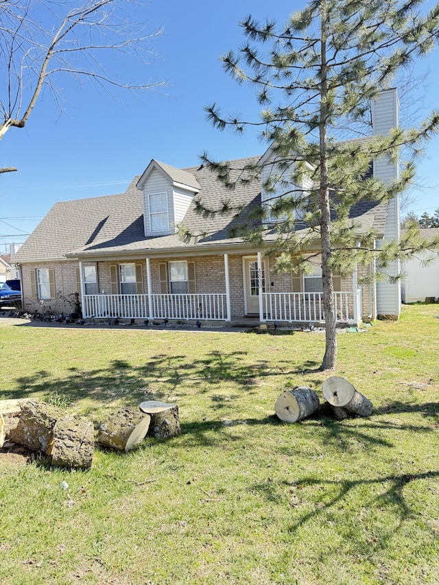 view of front of home featuring brick siding, a porch, a front lawn, and roof with shingles