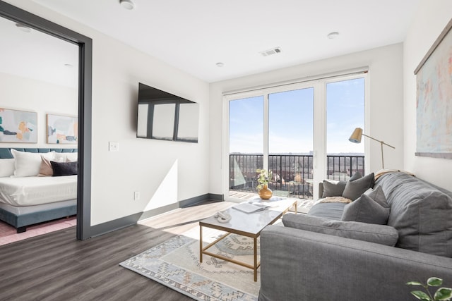 living room with dark wood-style floors, visible vents, and baseboards