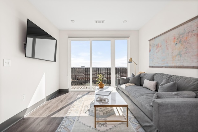 living area with wood finished floors, visible vents, and baseboards