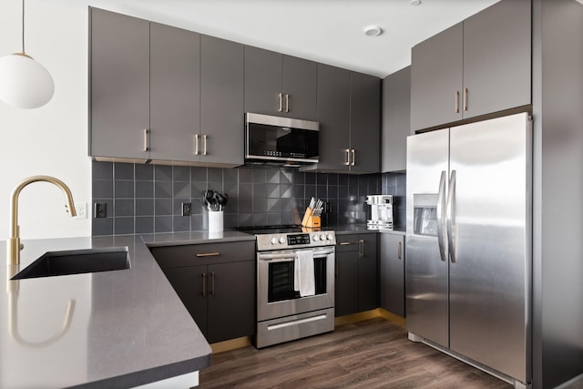 kitchen with a sink, tasteful backsplash, appliances with stainless steel finishes, and dark wood-style floors