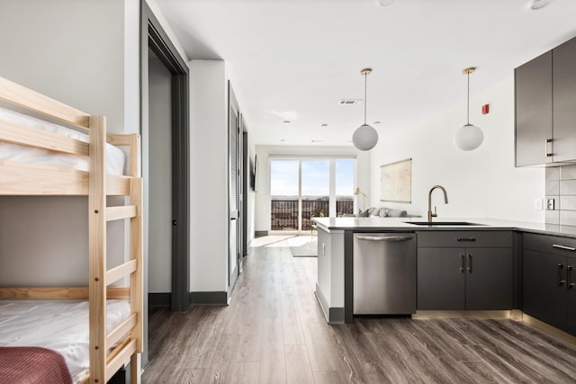 kitchen with dark wood-style flooring, dishwasher, a peninsula, and a sink