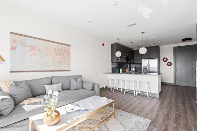 living room featuring dark wood-style floors, visible vents, and baseboards